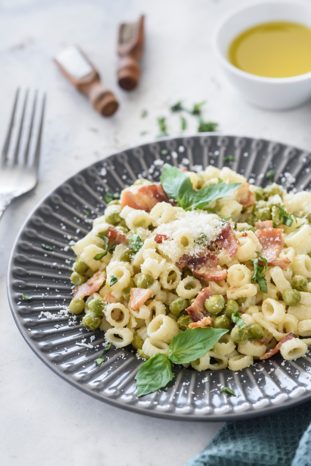 cook pasta with peas and bacon plated with a sprinkle of cheese on top