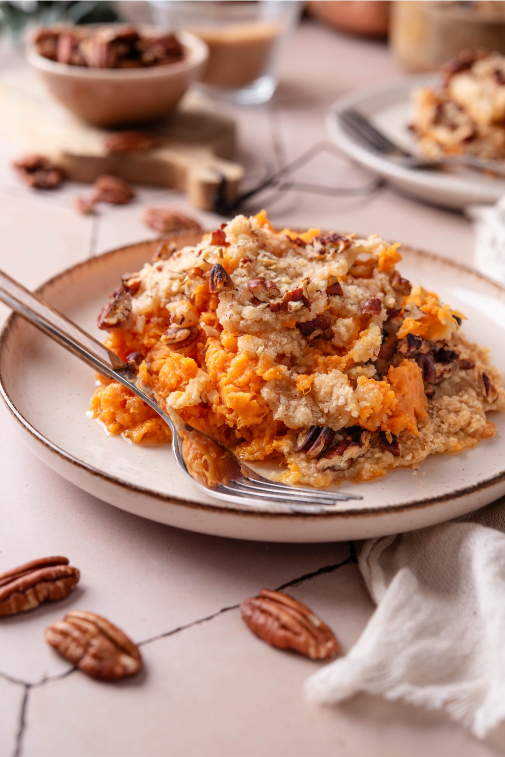 A plate with pumpkin casserole with crumbly pecan topping. A fork is next to it.