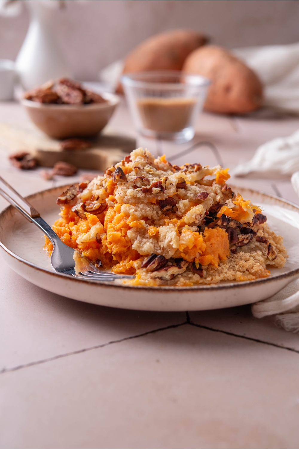 A plate with pumpkin casserole with crumbly pecan topping. A fork is next to it.