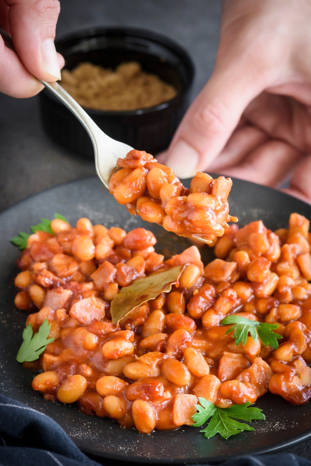 A fork full of baked beans over a plate
