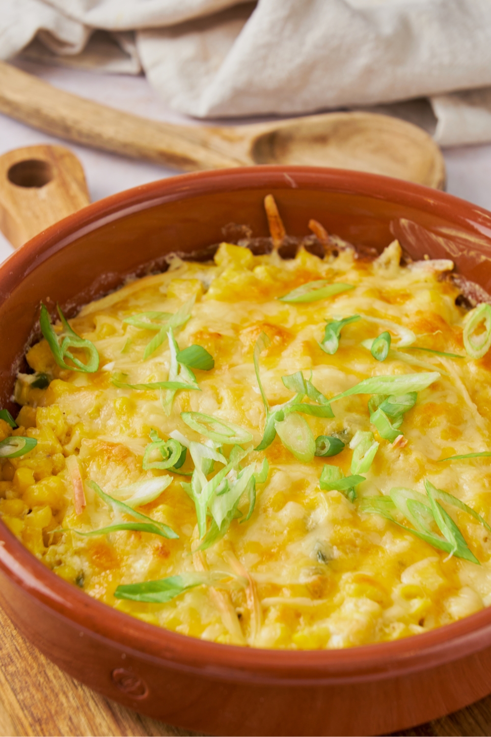 Melted cheese on top of jalapeno corn casserole in a red dish