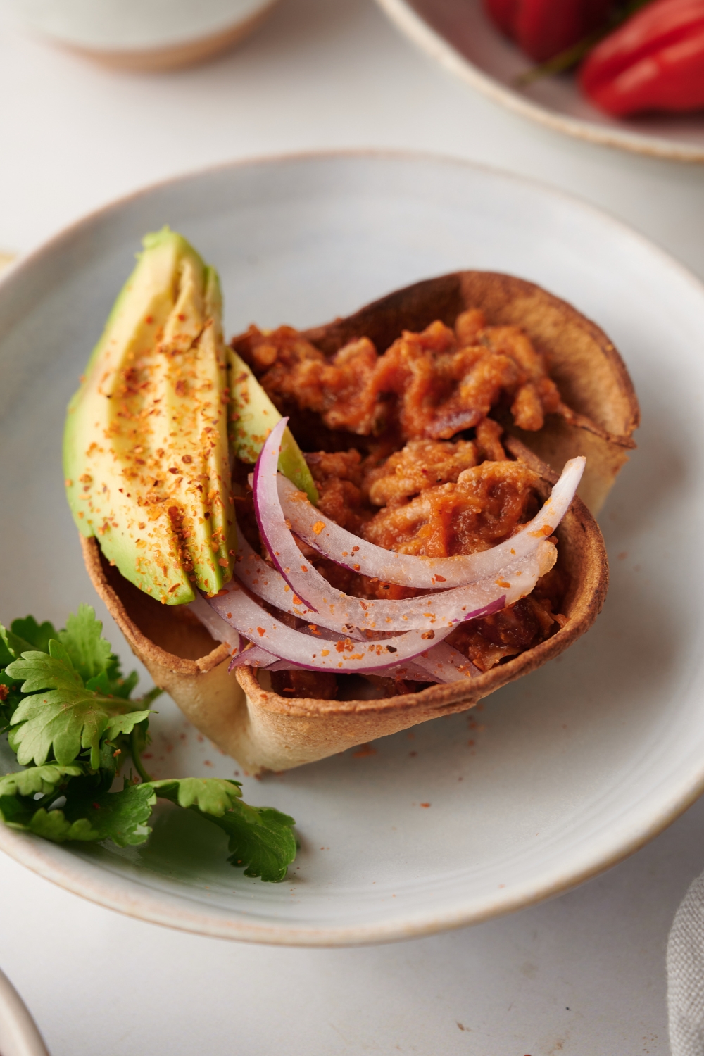 Cooked Mexican chili served in a tortilla bowl with avocado