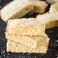 Three rectangular biscuits stacked on top of each other sprinkled with sugar on a cooling rack.