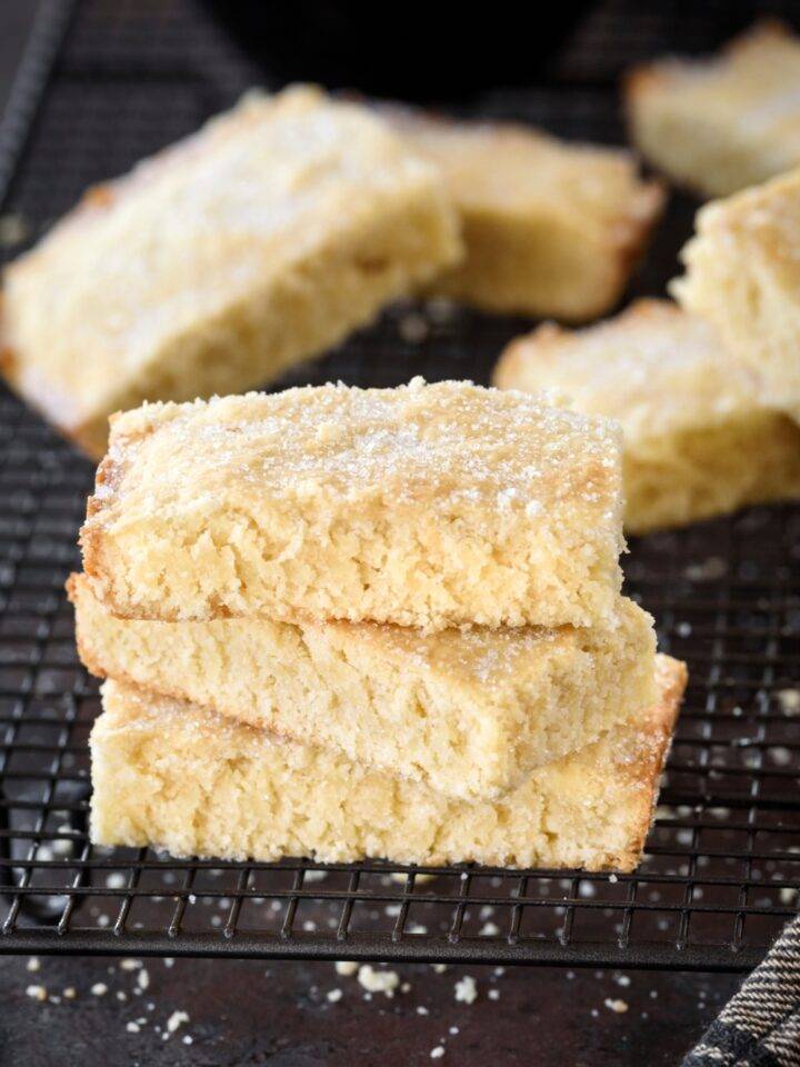 Three rectangular biscuits stacked on top of each other sprinkled with sugar on a cooling rack.