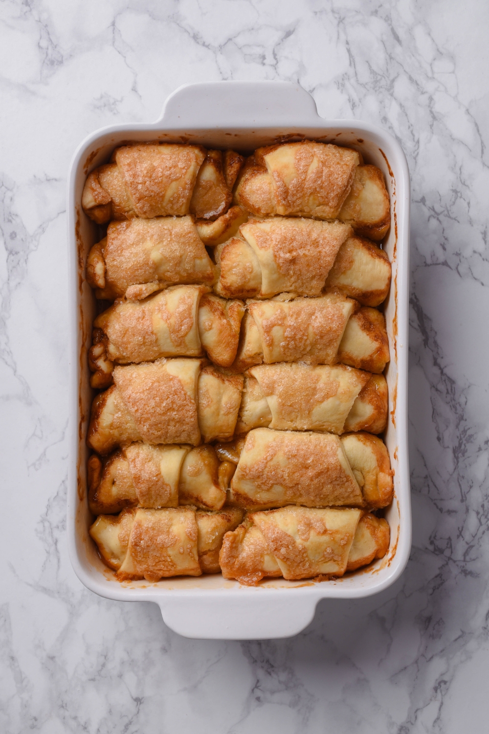 A casserole dish with baked apple dumplings with crescent rolls.