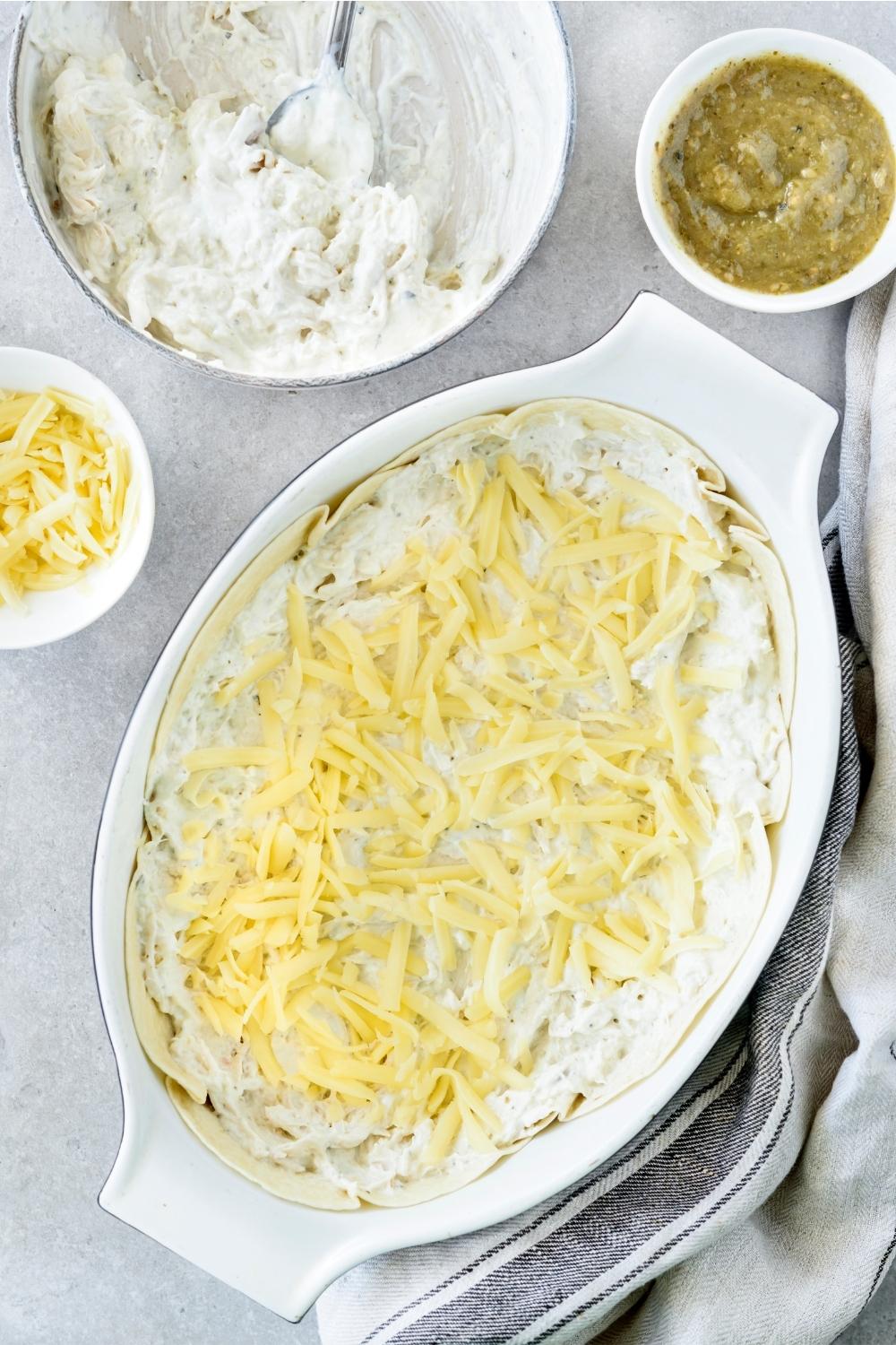 A casserole dish with a layer of flour tortillas and shredded cheese.