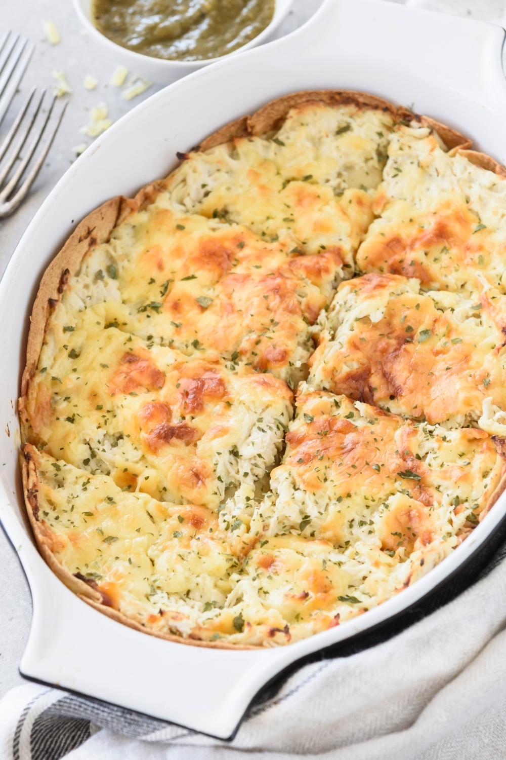 A casserole dish with green chicken enchilada casserole.