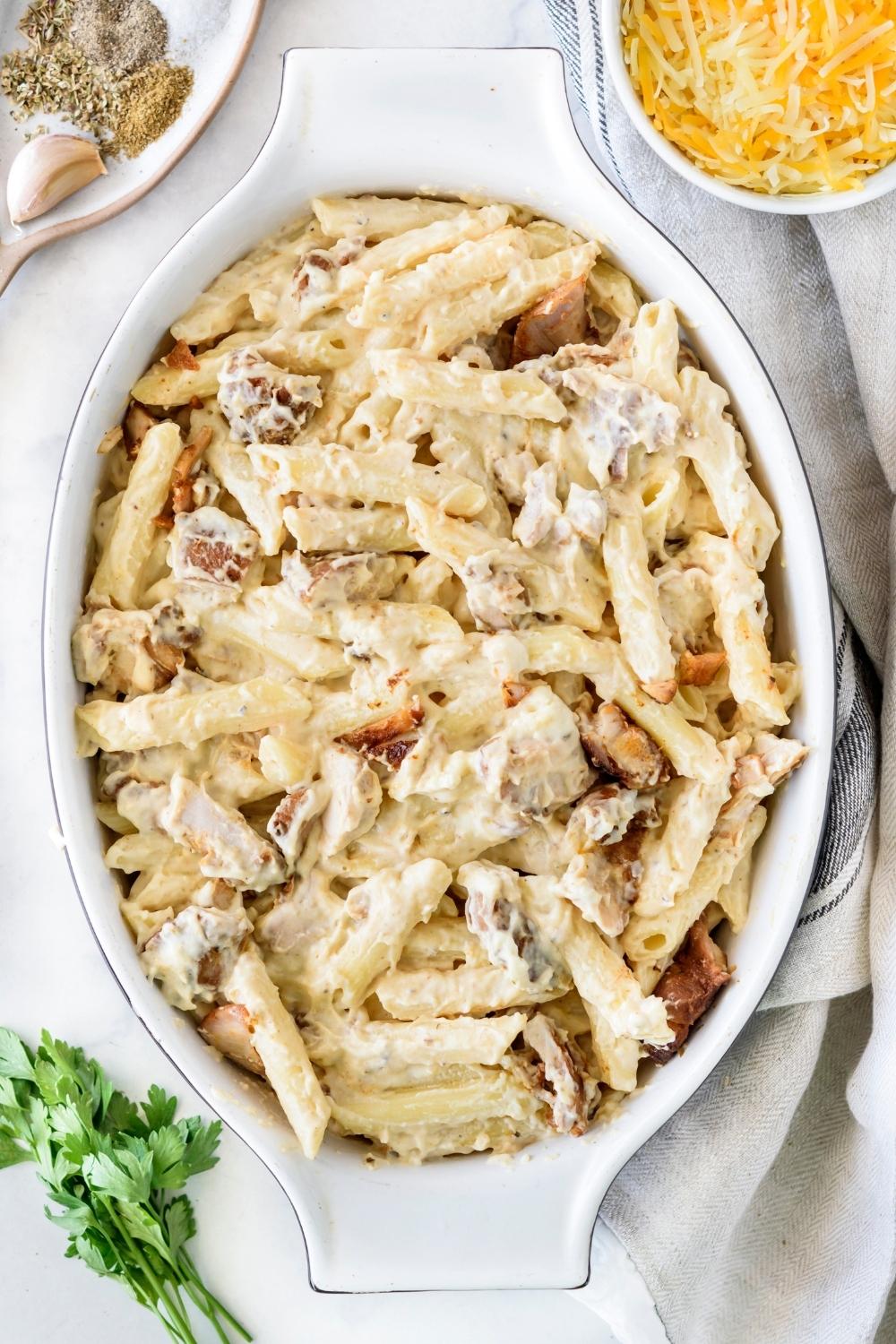 A casserole dish with the pasta chicken alfredo mixture in it.