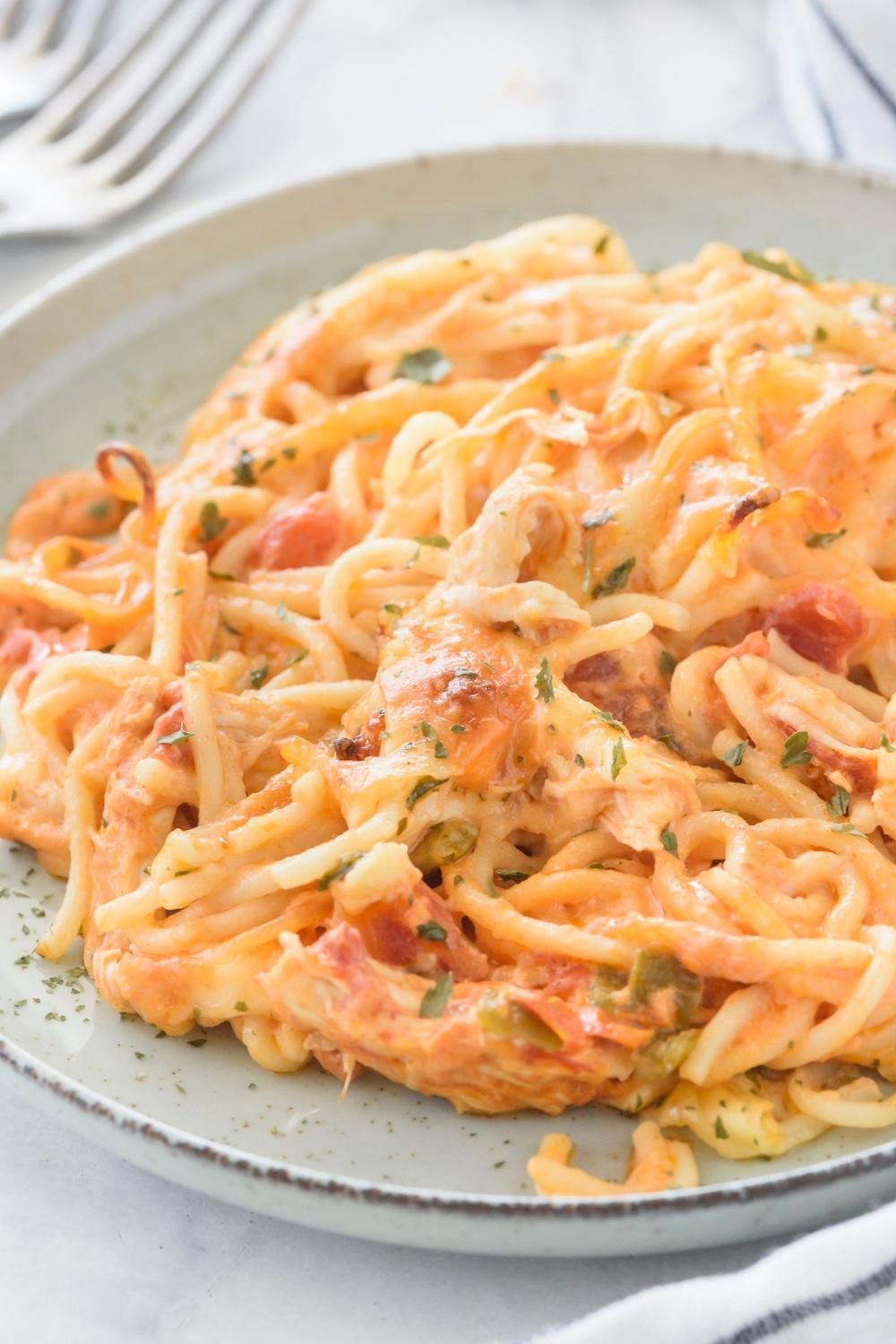 A plate with a portion of rotel chicken casserole garnished with parsley.