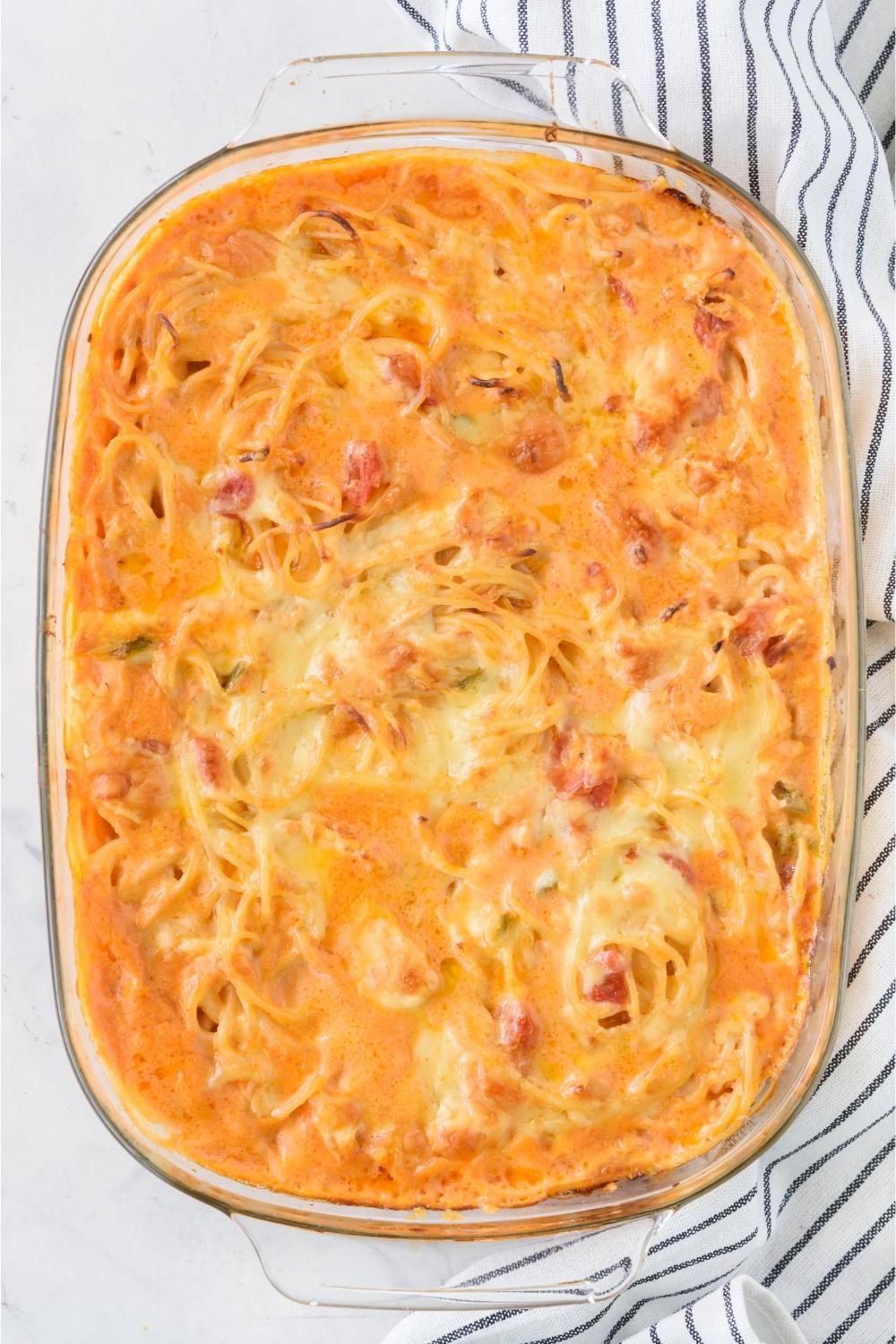 A casserole dish with baked rotel chicken spaghetti casserole in it.