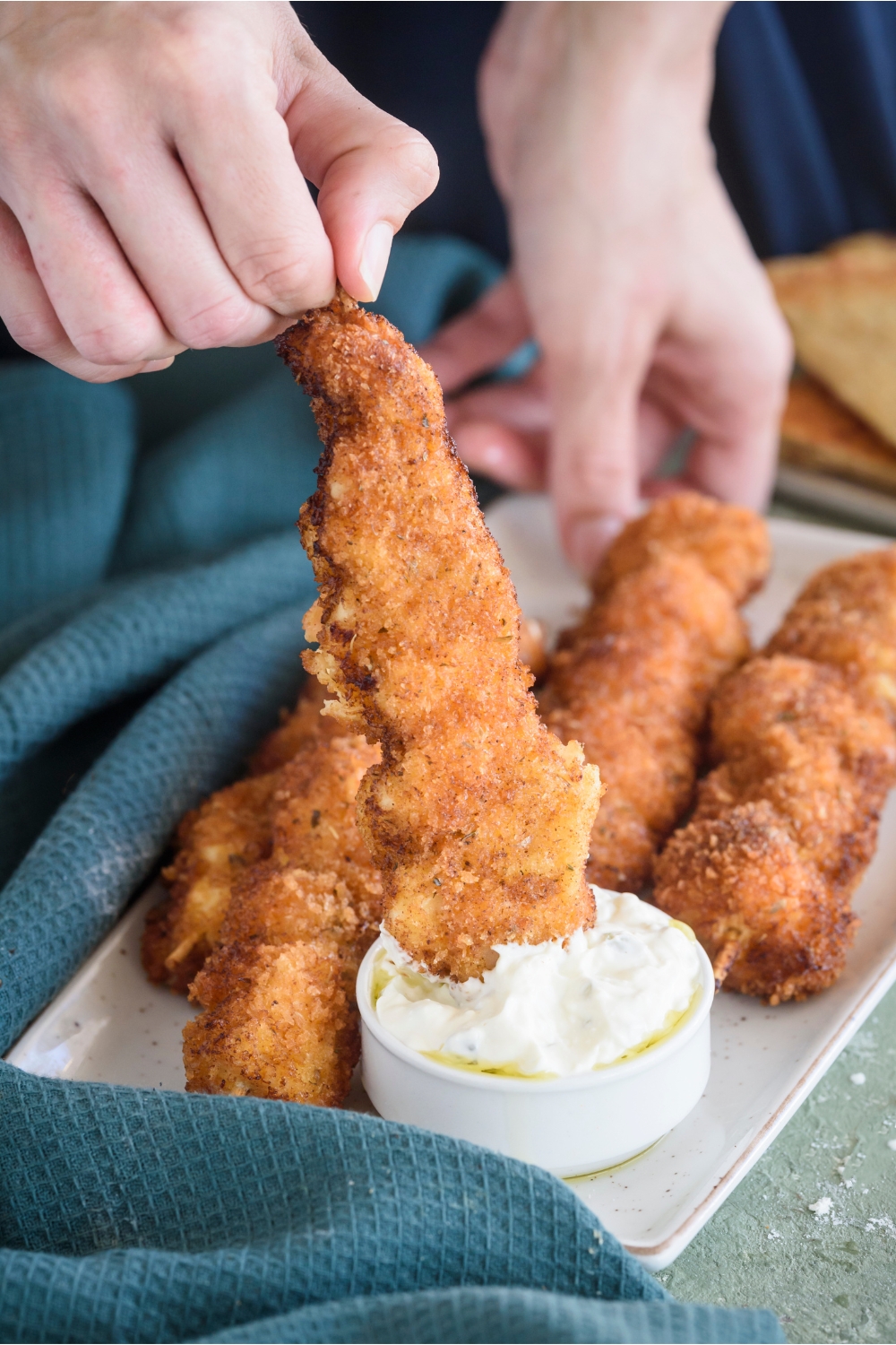 A fried chicken skewer being dipped in a bowl of white dipping sauce.