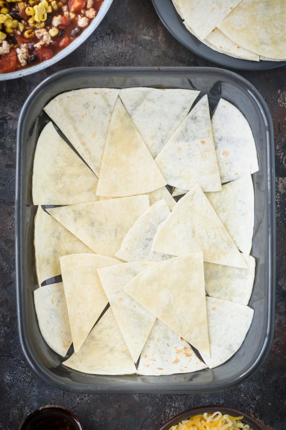 A casserole dish with the tortillas lining the bottom of the pan.