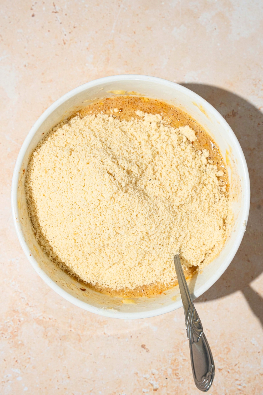 Almond flour on top of wet ingredients in a white bowl.