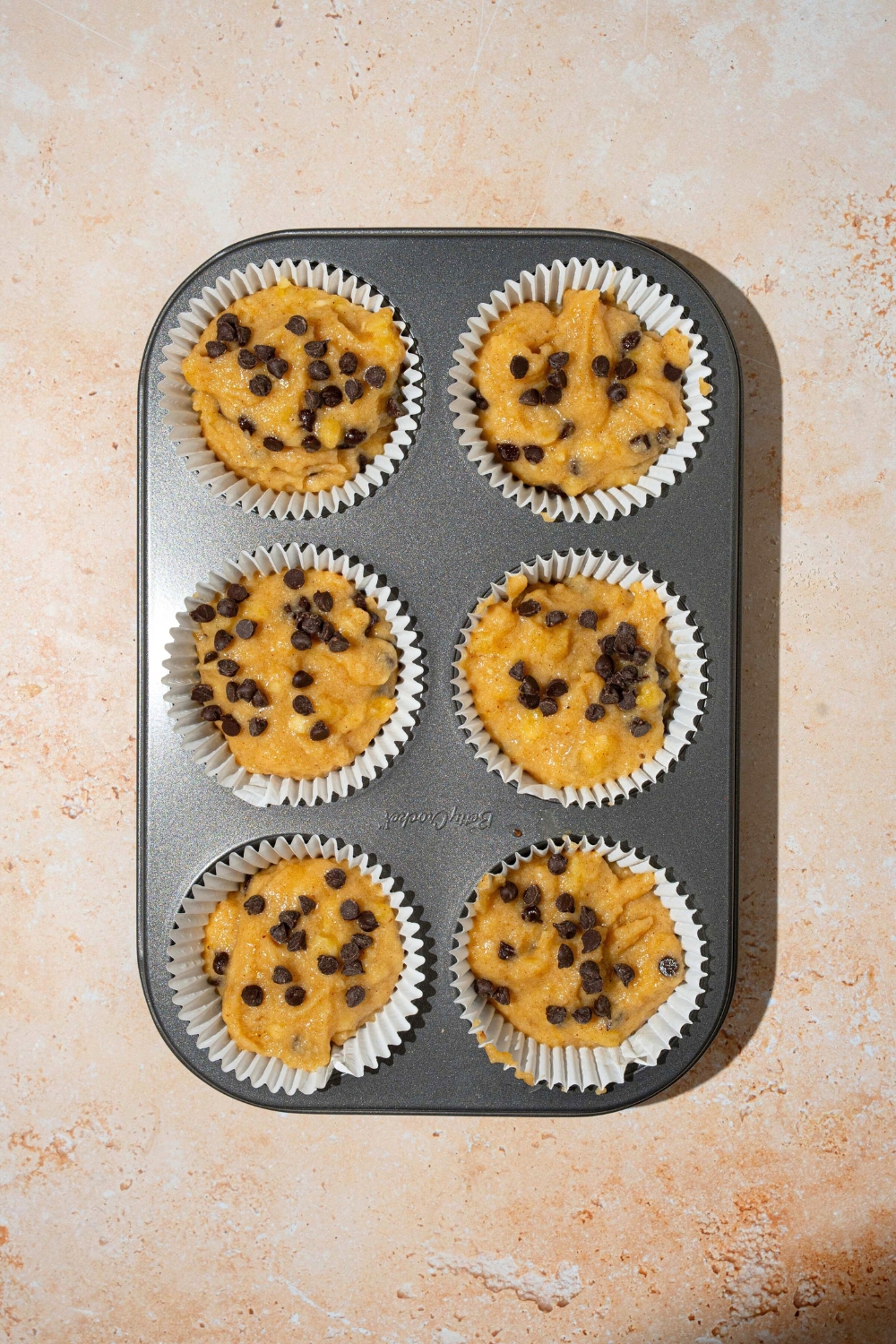 Almond flour, banana muffin batter in six muffin tins.