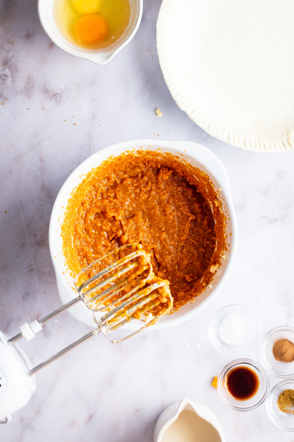 Two whisks above a bowl that is filled with sweet potato filling.