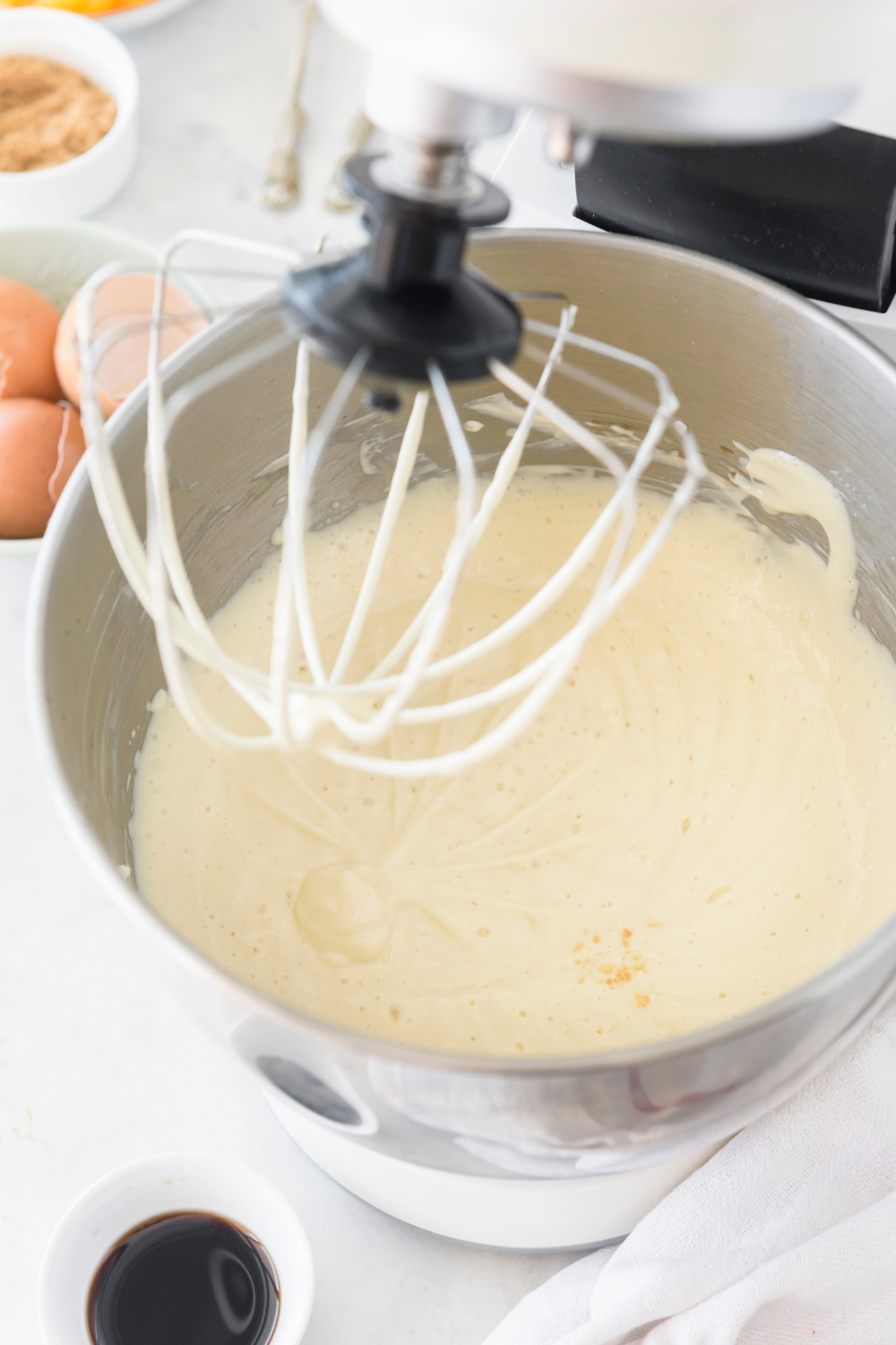 A mixing bowl with a stand mixer with the smooth cheesecake filling.