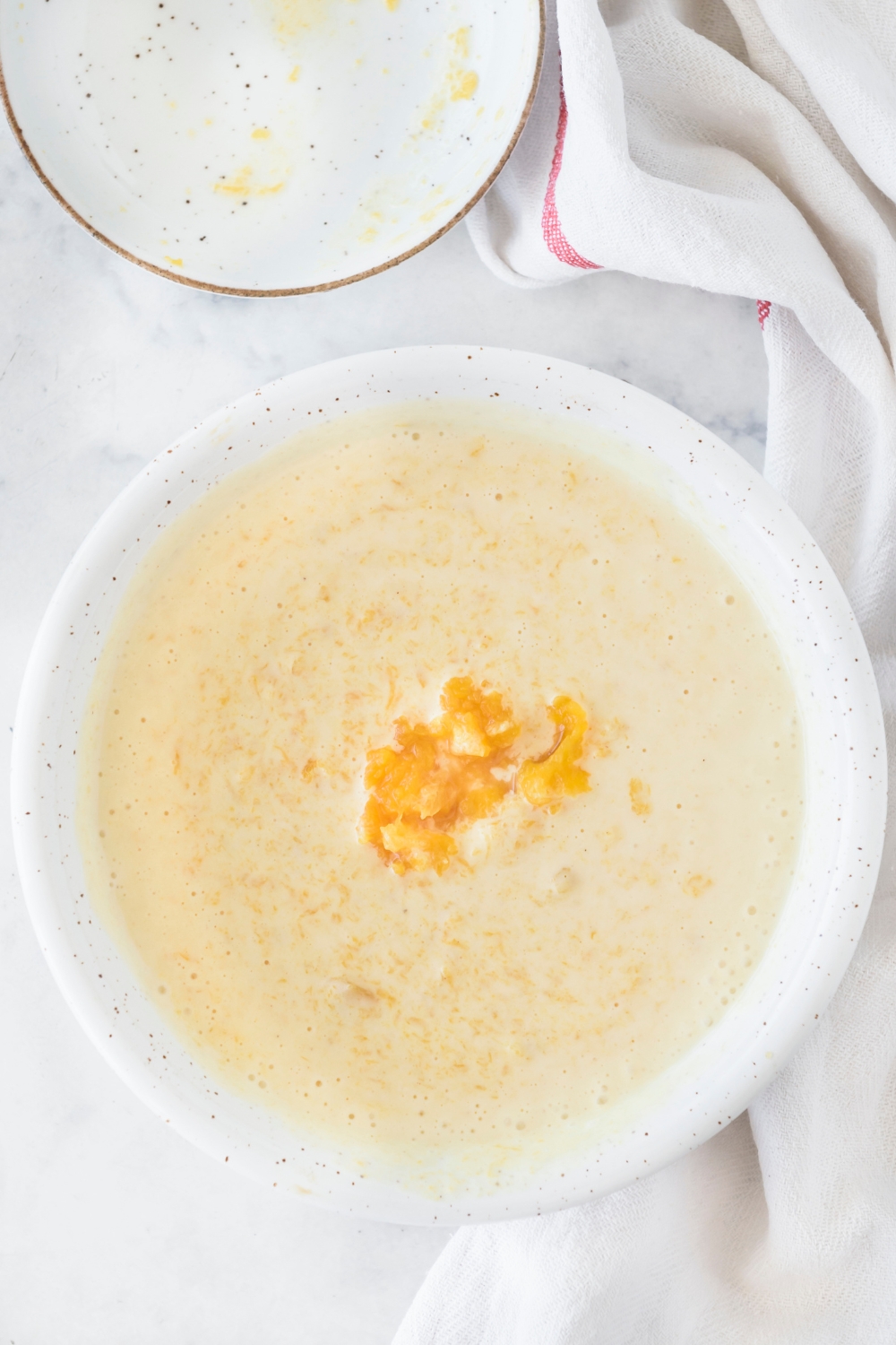 A bowl with half of the cheesecake batter and pumpkin puree added to it.