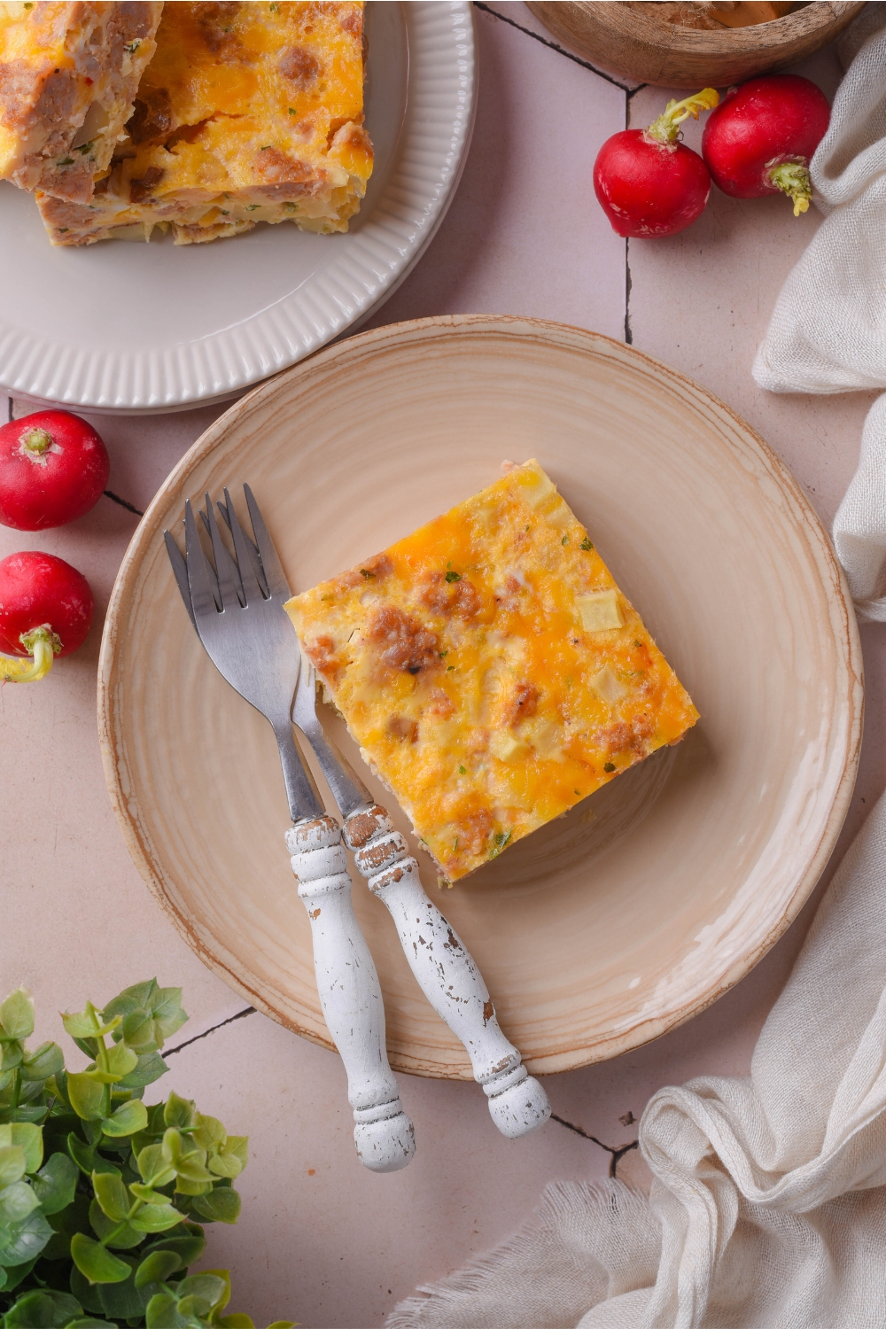 A plate with a square of hash brown casserole. A fork sits next to it.