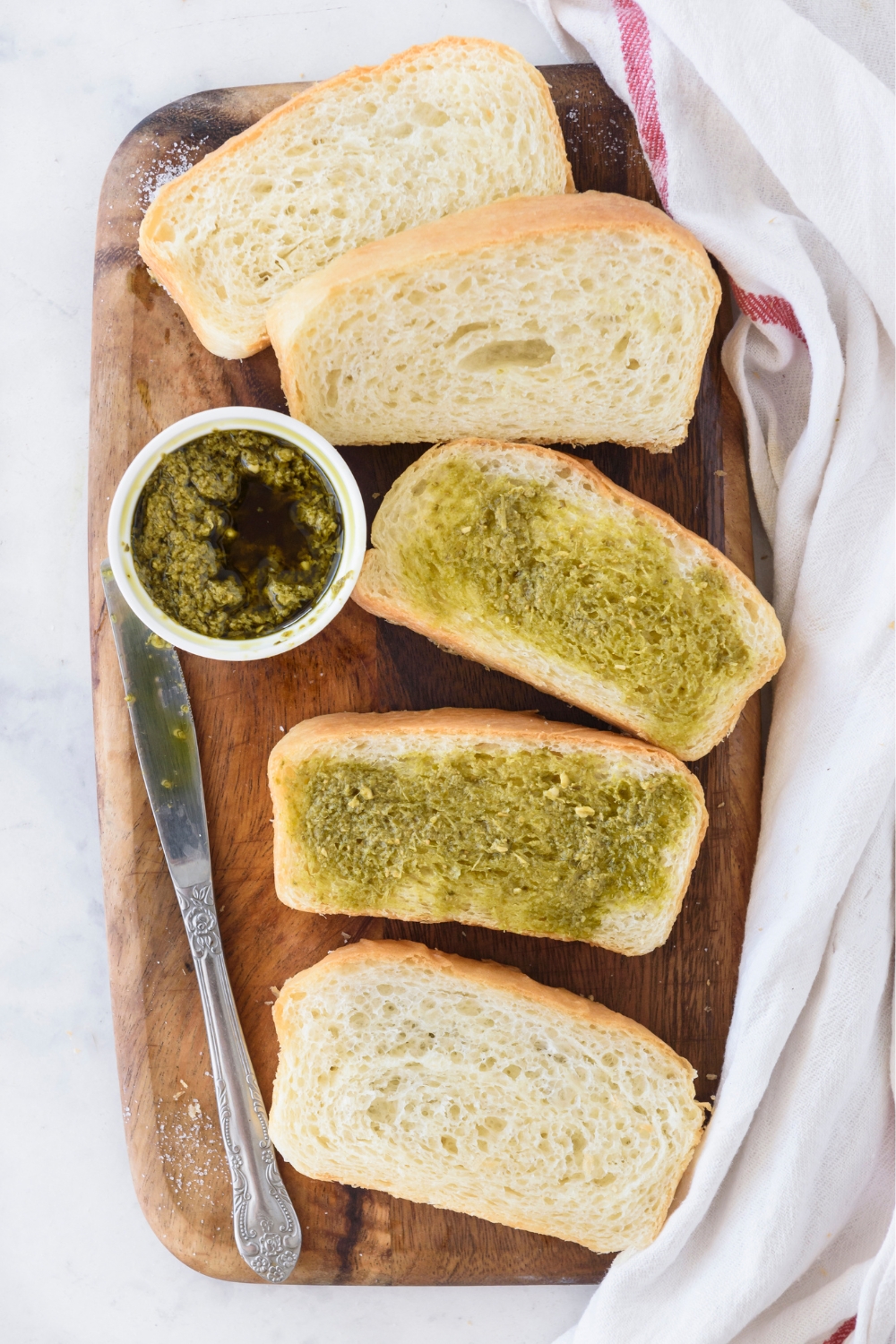 A wooden board with pesto and bread slices.