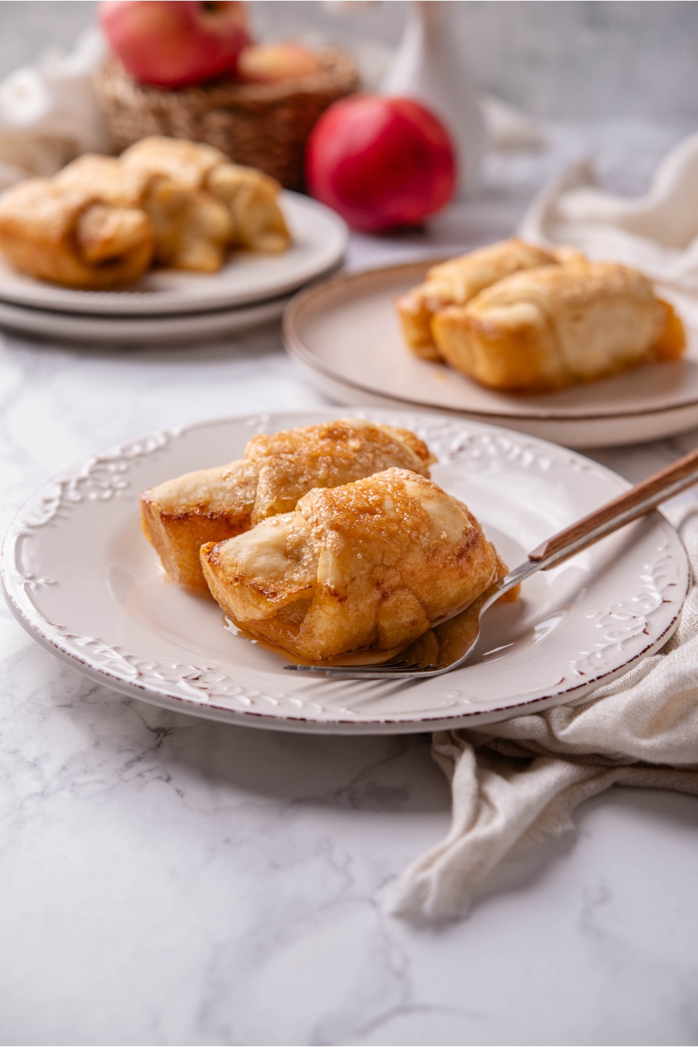 A plate with apple dumplings with crescent rolls and a fork next to them.