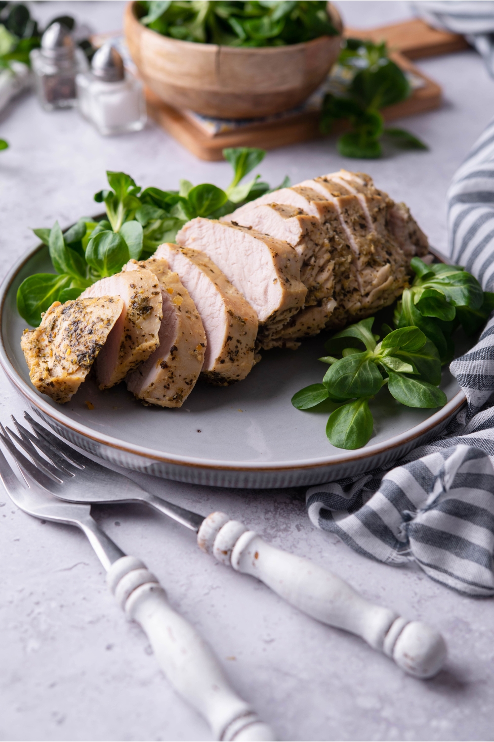 A bunch of turkey tenderloin slices on a grey plate.