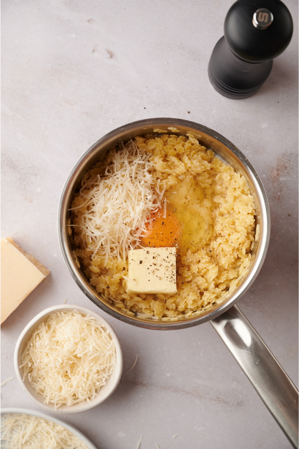 A sauce pot with and egg, milk, butter, and cheese added to cooked pastina.