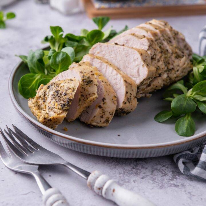 A plate with sliced turkey tenderloin on it.