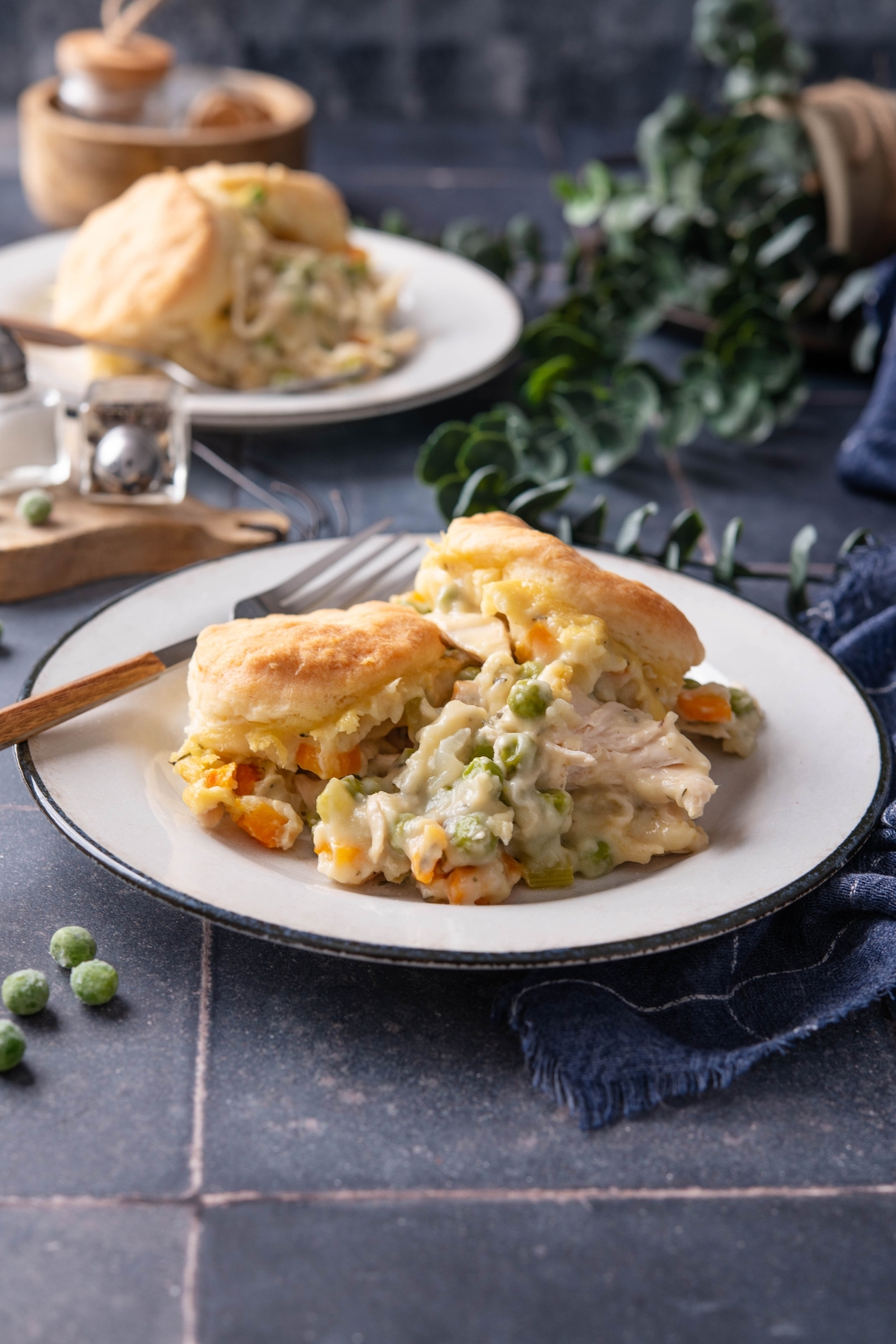 Two full plates of chicken pot pie with biscuits on a black countertop