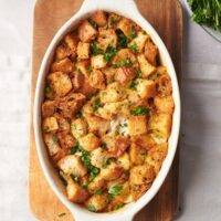 A baking dish filled with casserole topped with crispy stuffing and garnished with fresh herbs.