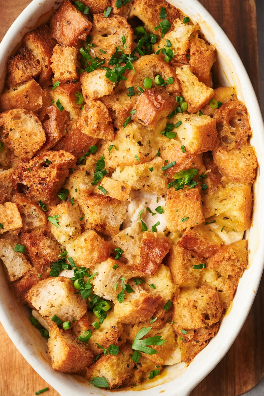 A baking dish filled with casserole topped with crispy stuffing and garnished with fresh herbs.