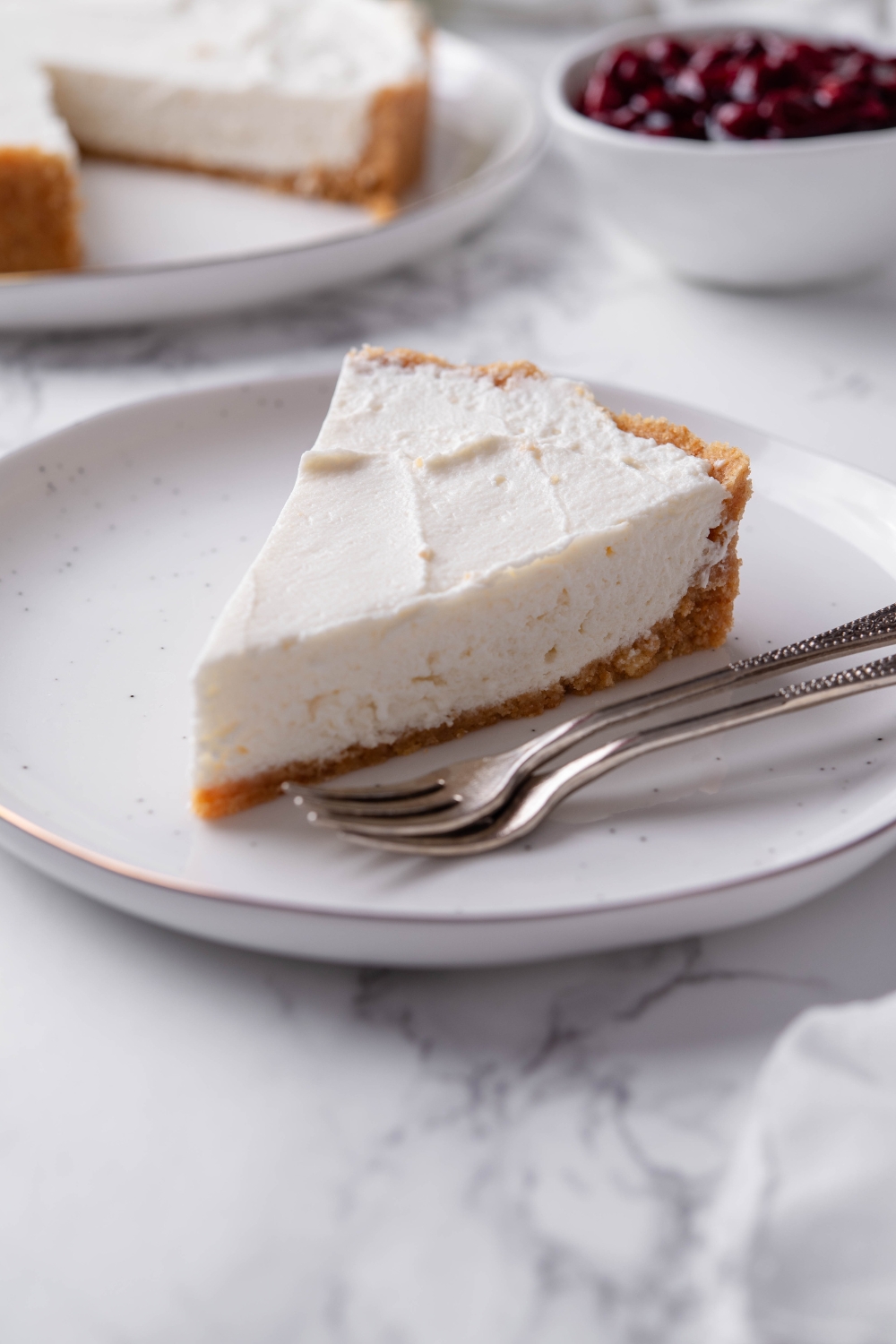 A serving of cream cheese pie on a white plate with two forks on the plate.