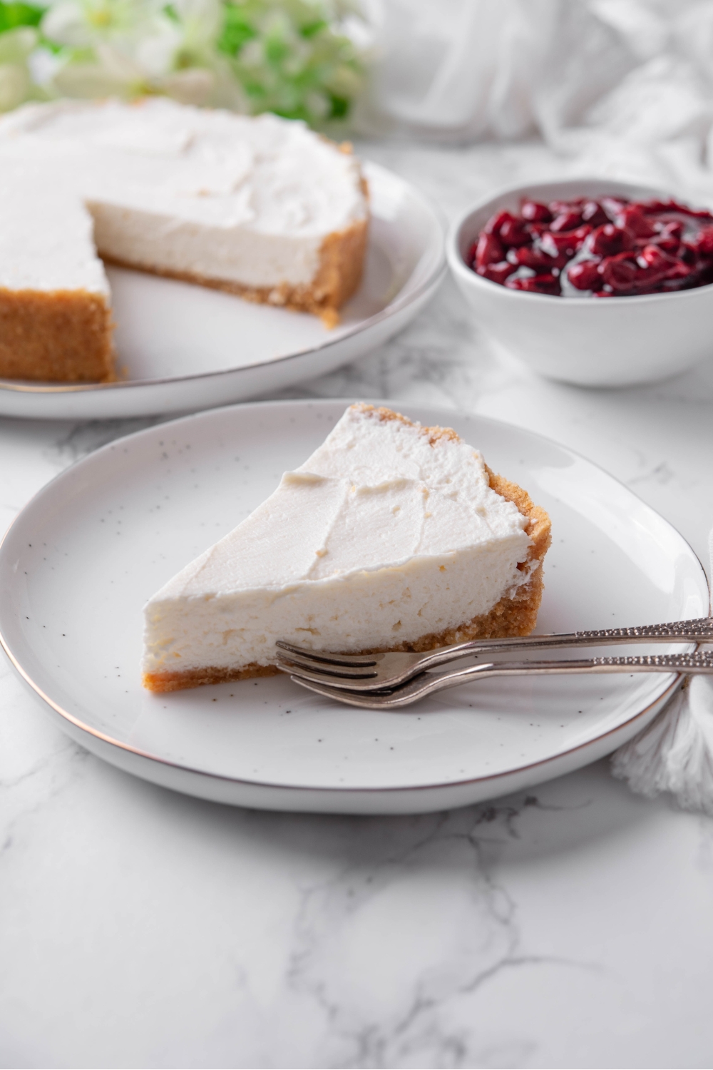 A serving of cream cheese pie on a white plate with two forks on the plate.