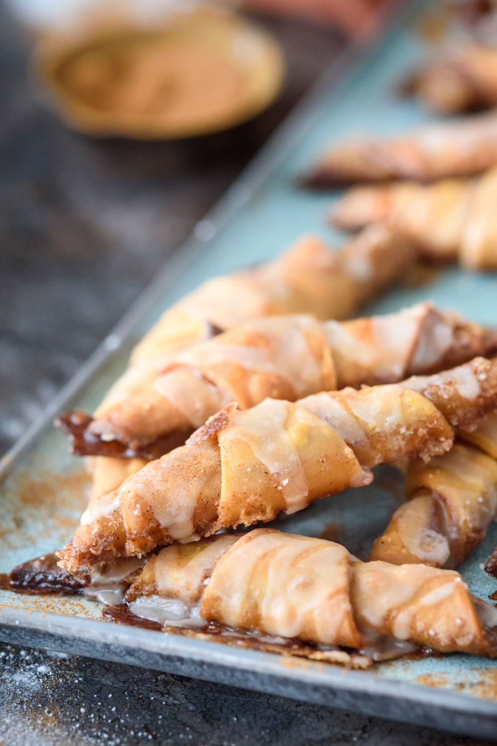 Golden Brown Crescent Cinnamon Rolls sit on a blue platter drizzled with icing.