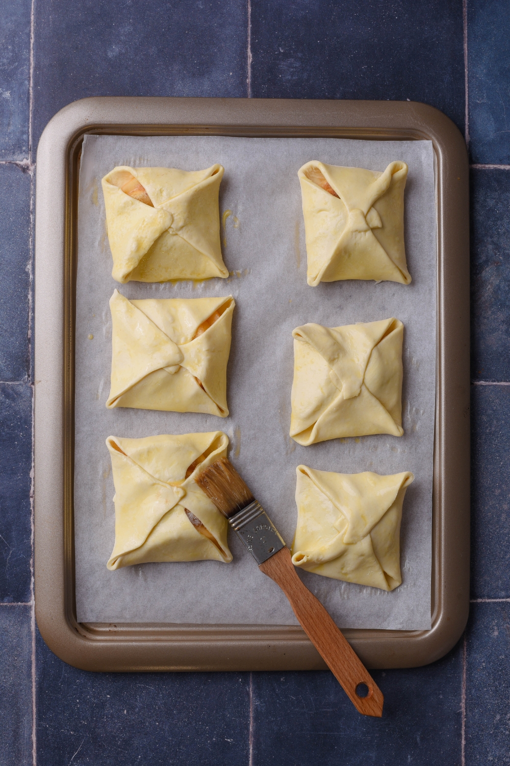 A baking sheet with parchment paper and the pastry pockets on the tray.