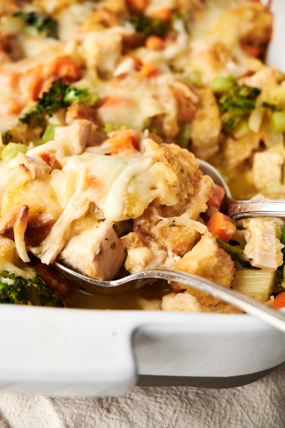 A fork and spoon dishing out a serving of chicken broccoli stuffing.