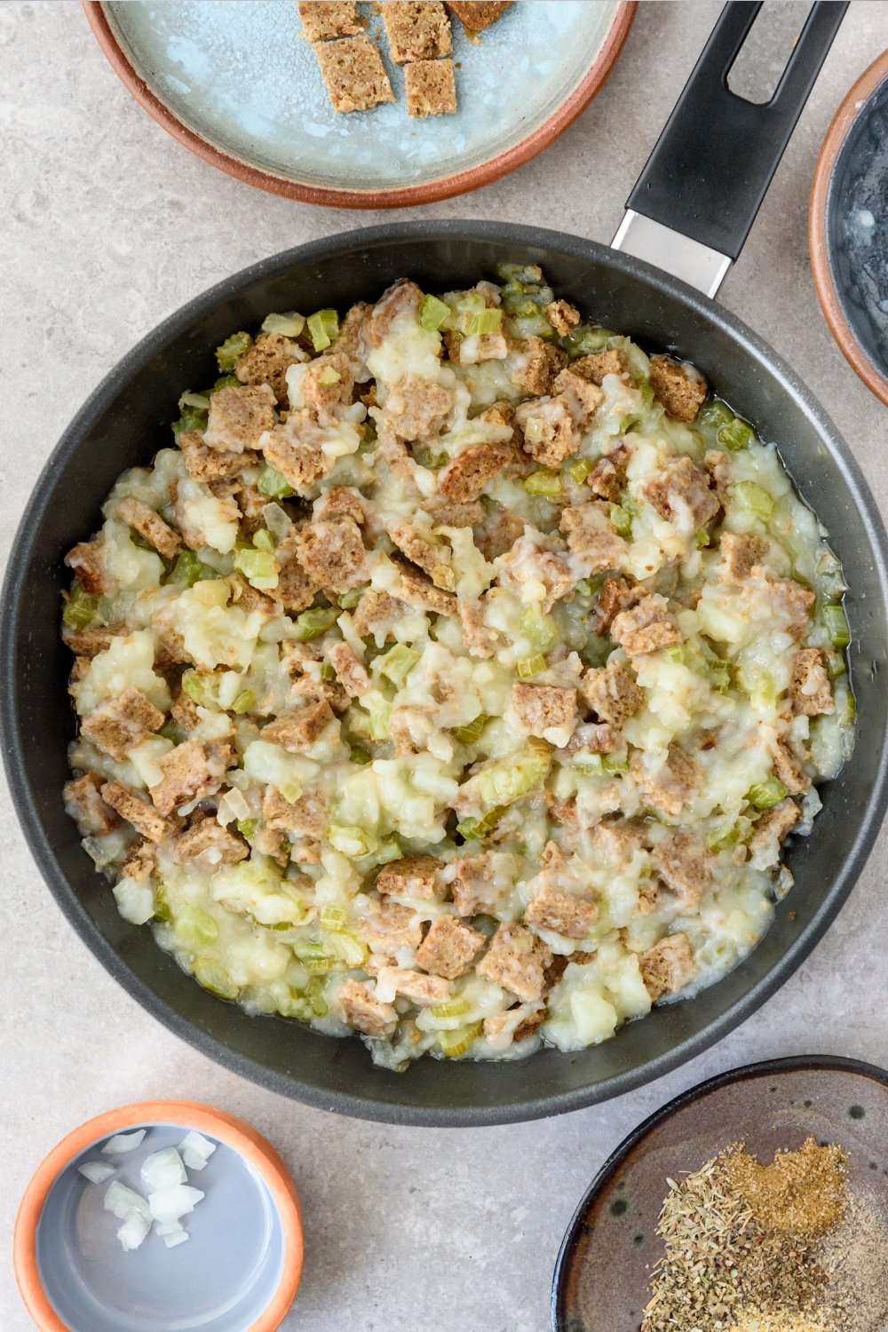 A black frying pan full of Amish potato stuffing on a gray counter.