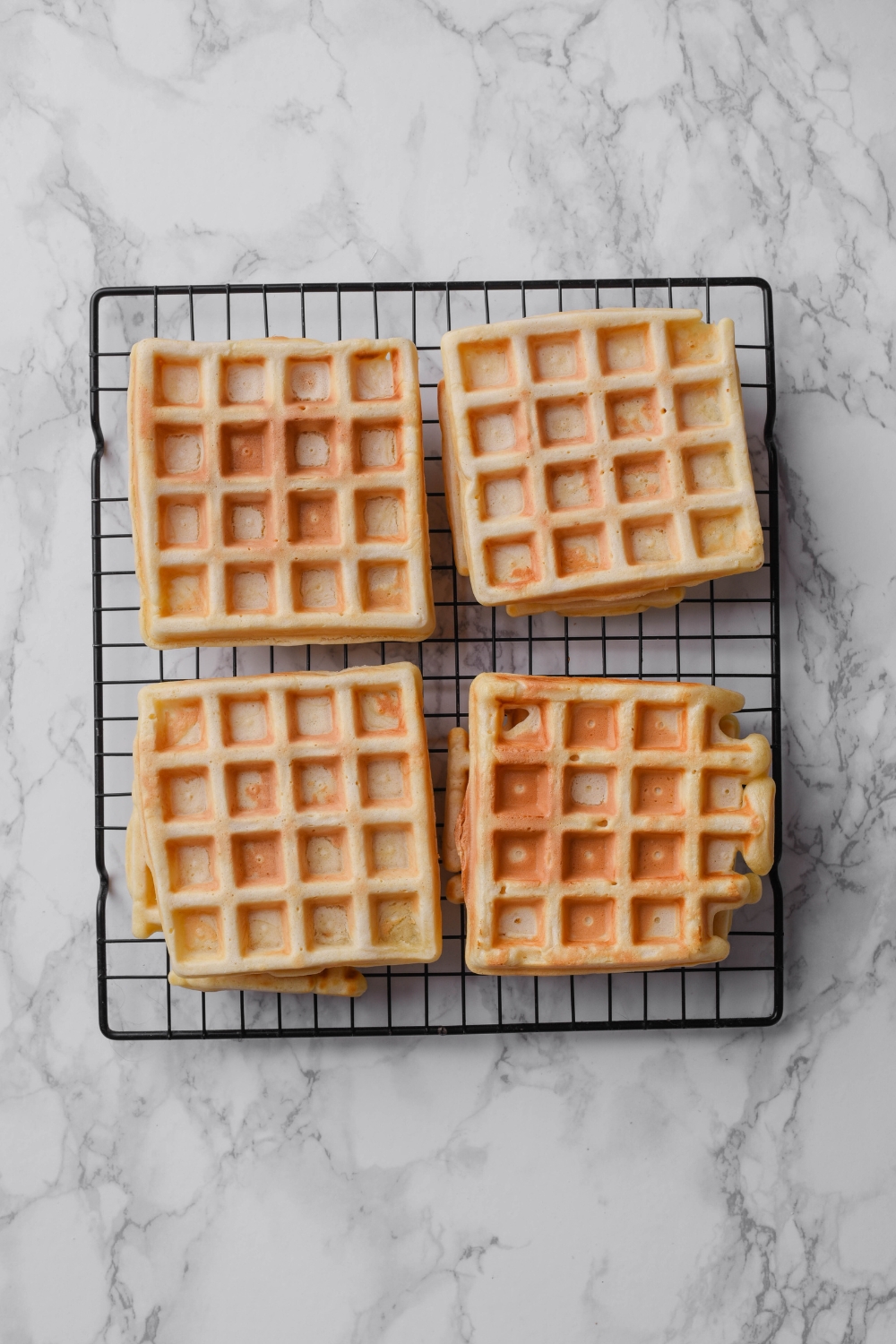 Four square waffles on a wire rack.