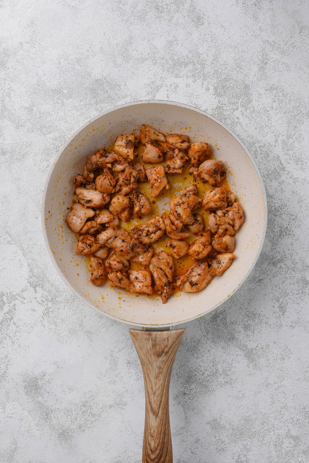 A skillet with cooked and seasoned chicken pieces in it.