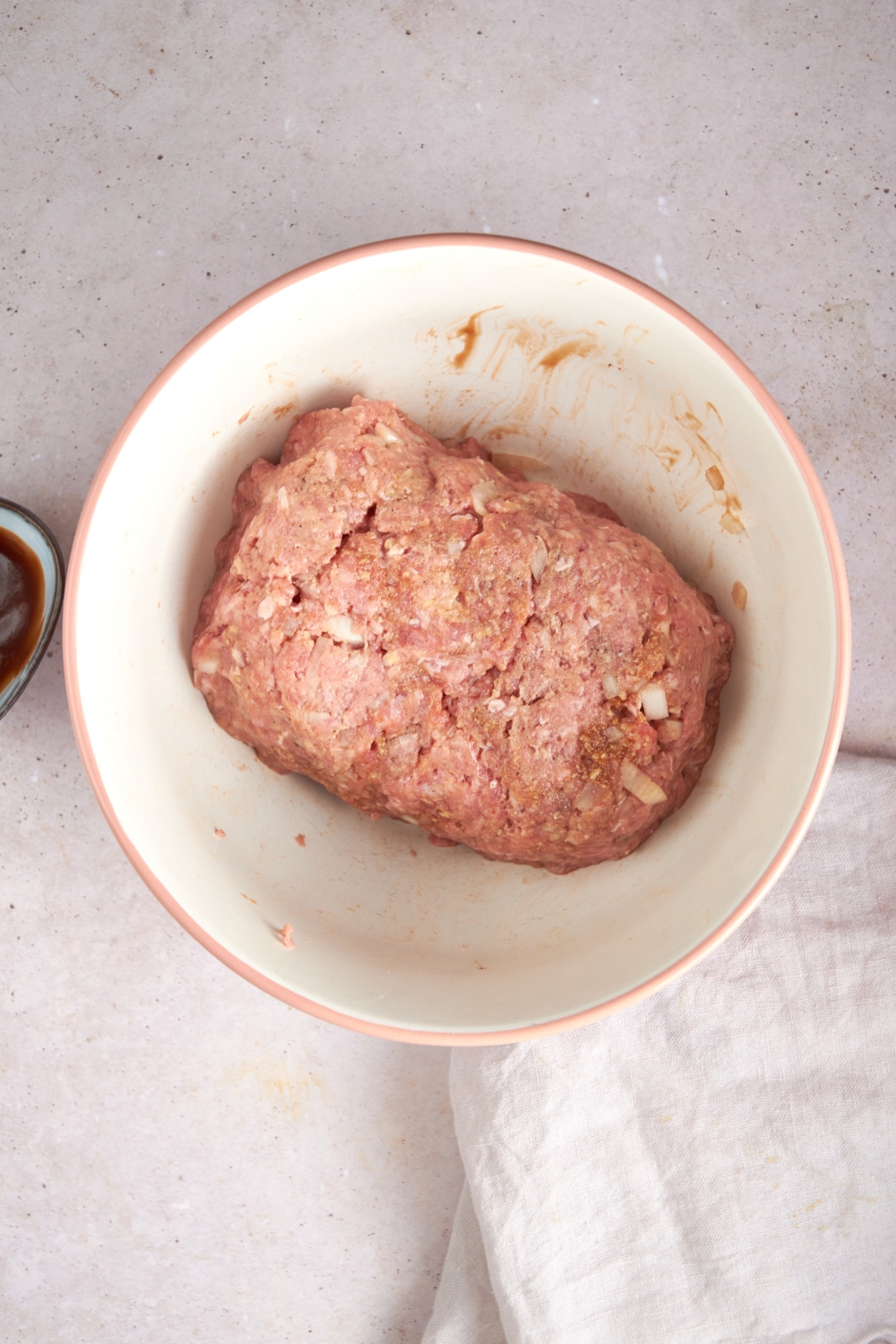 An uncooked meatloaf in a white mixing bowl.