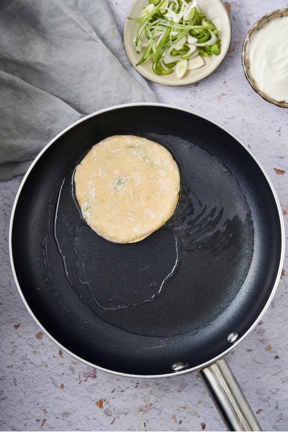 One mashed potato pancake in a frying pan with oil.