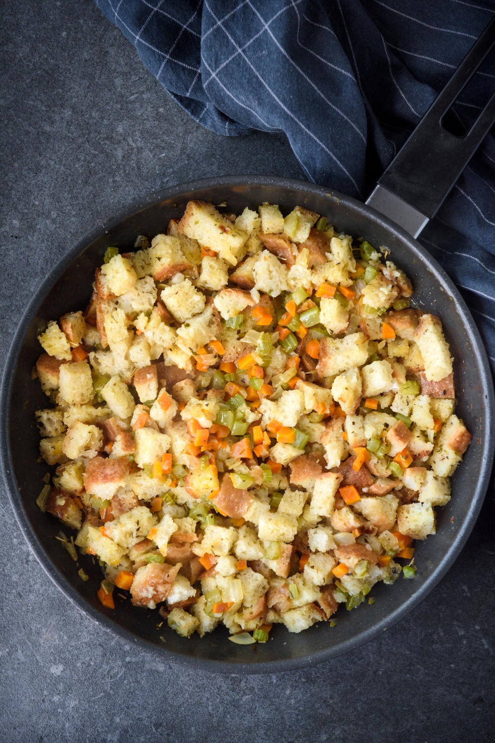 A skillet filled with stovetop stuffing mixed with diced celery, carrots, and onion.