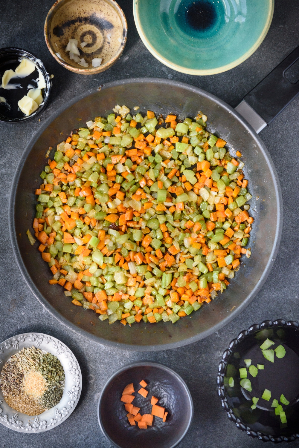A skillet with diced celery, carrots, and onion cooking in it.