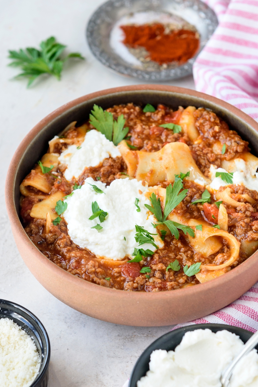 A bowl of lasagna soup with chunks of ground beef and cooked pasta in red sauce. The soup is garnished with fresh herbs and topped with cheese.