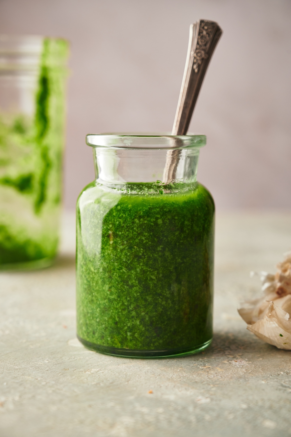 A jar of pesto with a spoon in it.