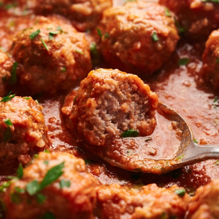 Cooked meatballs in a red sauce with a spoon