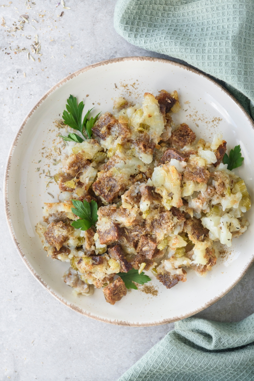 A white plate full of Amish Potato Stuffing garnished with fresh parsley.