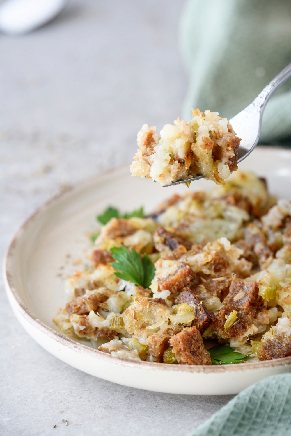 A plate of Amish Potato Stuffing. A fork has a bite of stuffing on it.