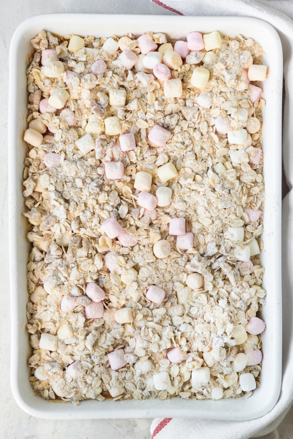 A white casserole dish full of Boston Market Sweet Potato Casserole topped with oat crumble and mini marshmallows.