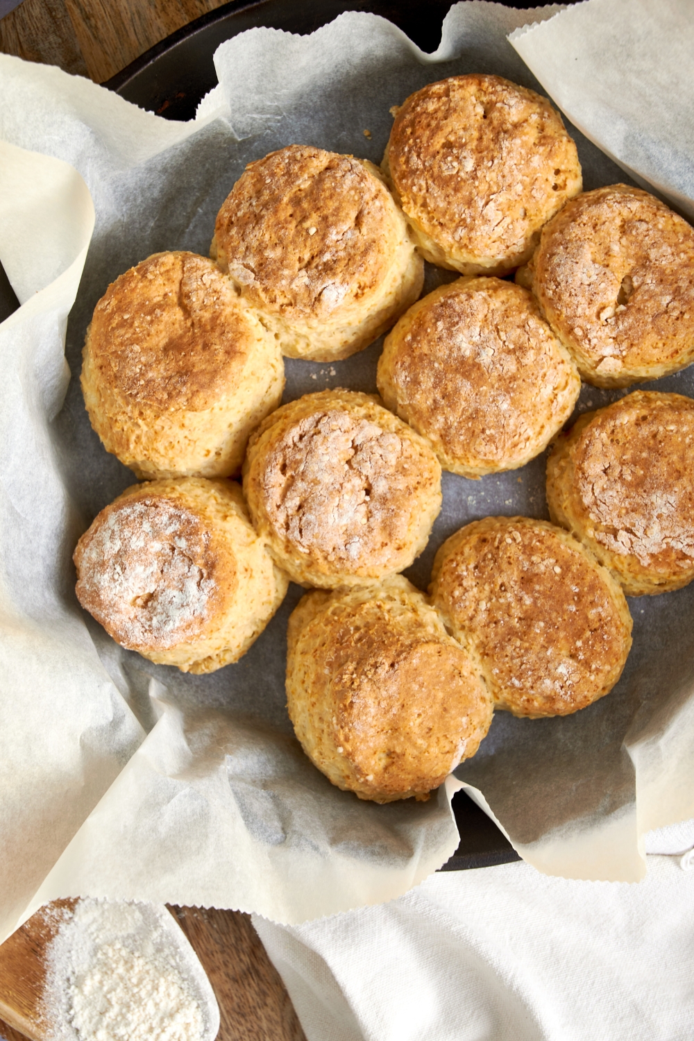 Ten cathead biscuits, golden brown, on a parchment paper lined pan.