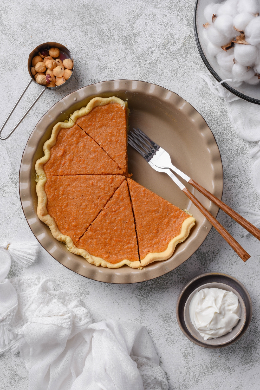 A sweet potato pie that has been sliced into equal-sized pieces with some pieces missing. There are two forks in the pie pan.